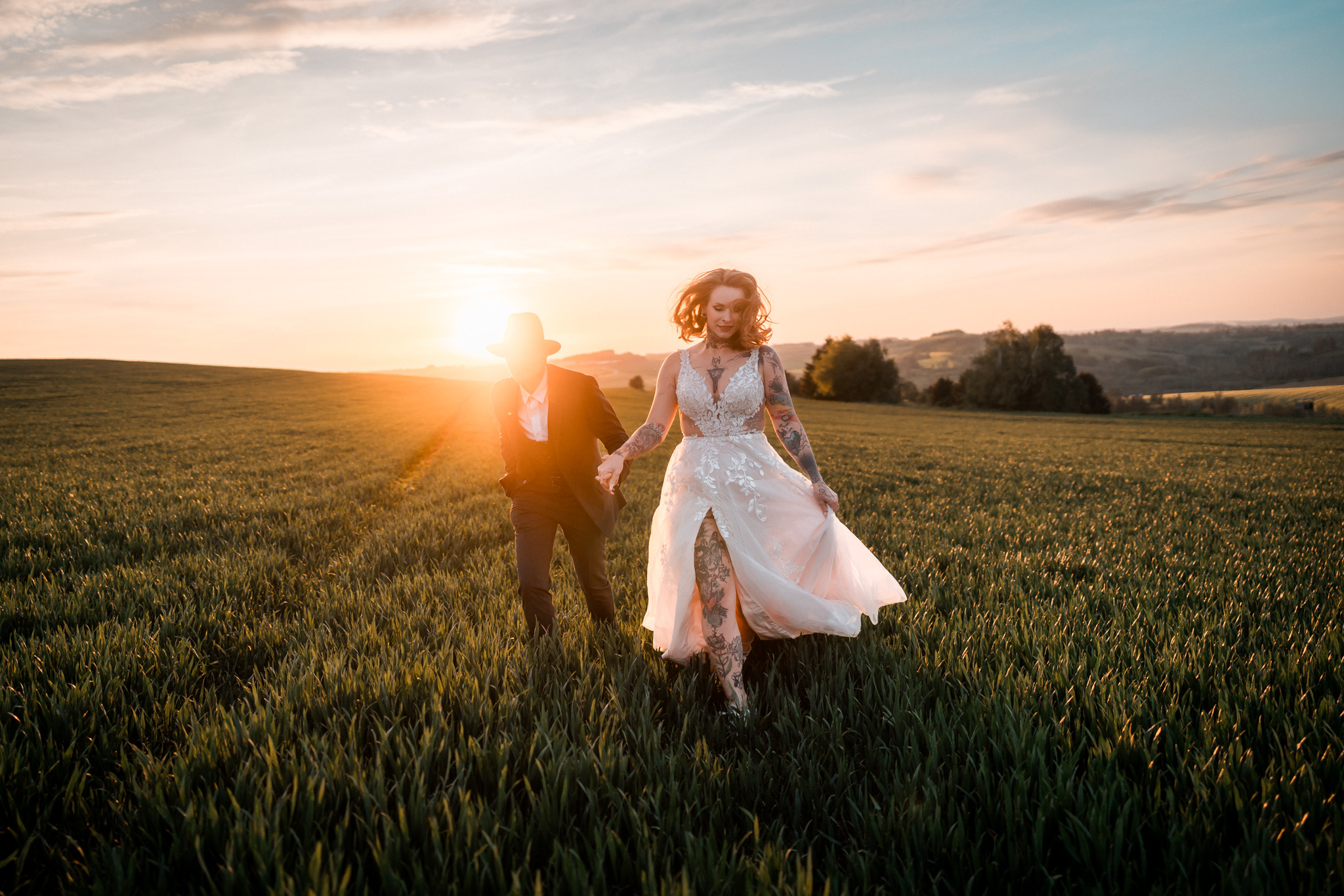 Nevěsta a ženich ve svatebních šatech na louce při západu slunce, Za vratama, Bransouze, 2024